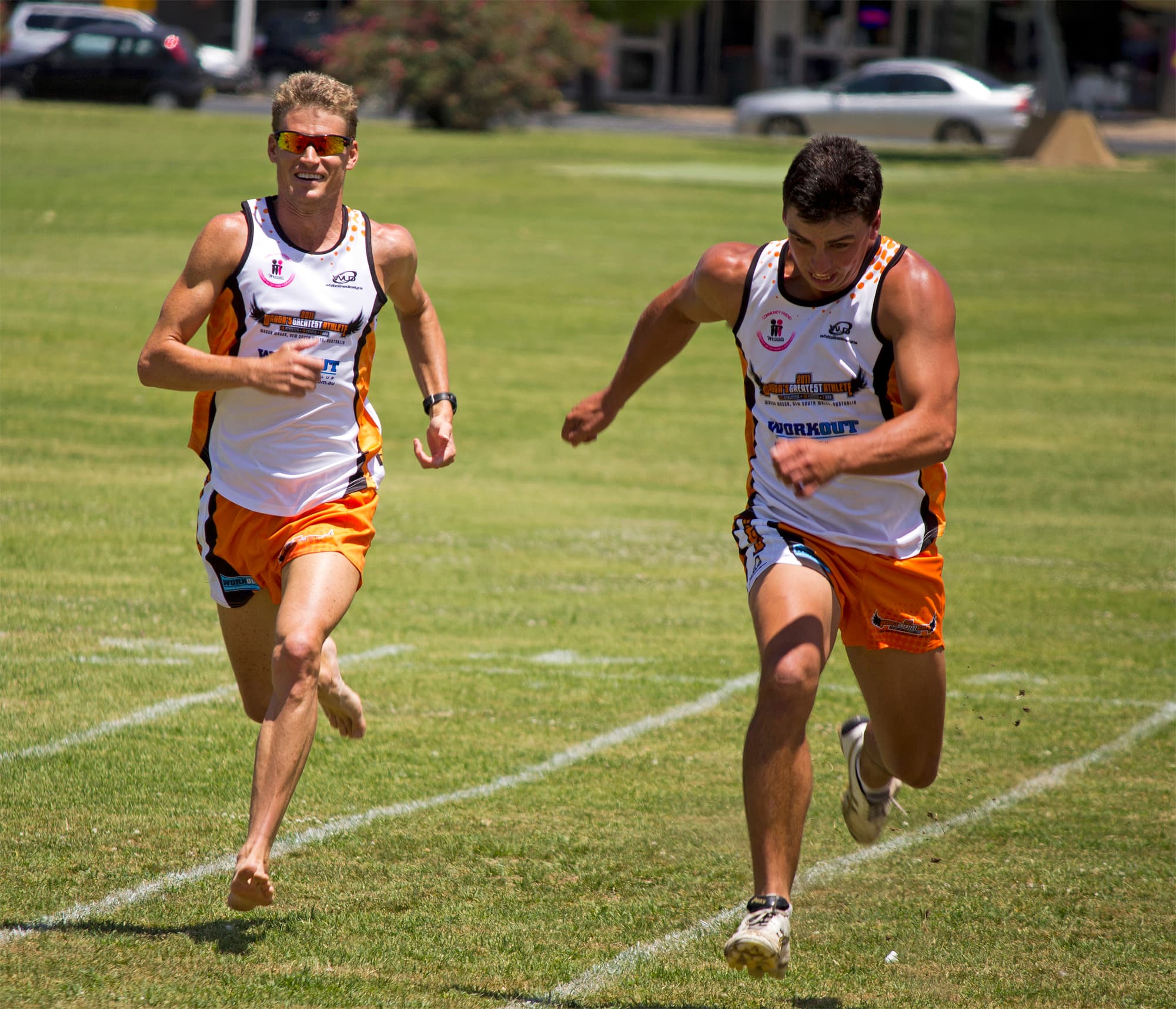 Two athletes mid-stride during a 50-meter sprint, arms driving in opposition to their legs