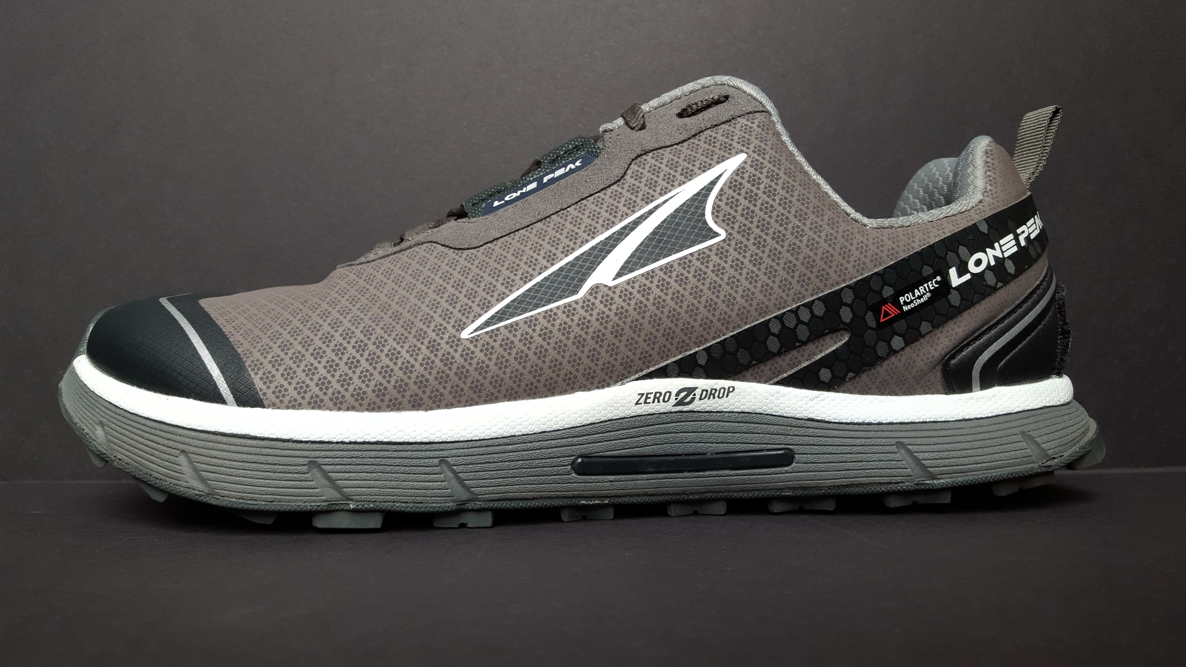 Side view of an Altra Lone Peak trail running shoe on a wooden surface
